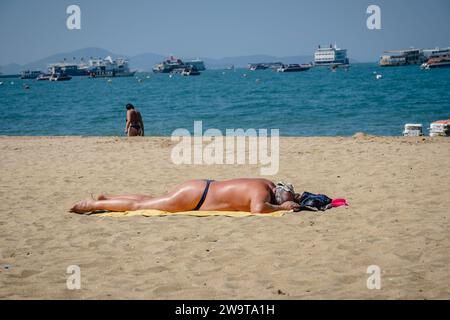 Pattaya, Thailandia. 27 dicembre 2023. Un vecchio turista che indossa una corda a forma di G viene visto dormire di giorno, sulla spiaggia di Pattaya, nella città di Pattaya, Thailandia. La spiaggia di Pattaya è una rinomata destinazione turistica in Thailandia. Ma mentre la città di Pattaya si è guadagnata una reputazione per la sua vivace vita notturna e le opzioni di intrattenimento, non è focalizzata esclusivamente sul servizio di ristorazione per viaggiatori singoli maschi. Oltre alla sua vita notturna, la città attrae diversi turisti, tra cui famiglie, coppie e individui di tutte le età, per lo shopping, le attività acquatiche e il relax sul mare. (Immagine di credito: © Nathalie Jamois/SOPA Image Foto Stock