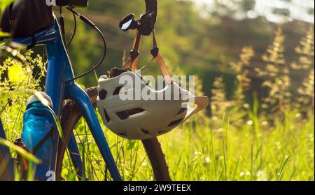 Bicicletta con un casco appeso al manubrio su uno sfondo di erba verde. Primo piano. Foto Stock