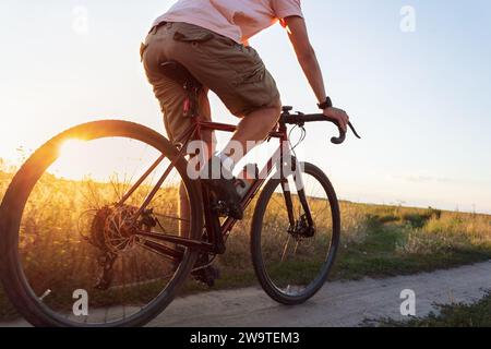 Ciclista sul campo. Un giovane sportivo cavalca in bicicletta al tramonto con sunbeam. Concetto di stile di vita attivo. Foto Stock
