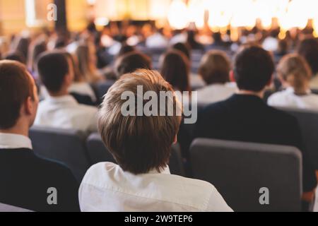 Pubblico scolastico gli studenti in una sala guardano lo spettacolo teatrale musicale della scuola su un palco, gli adolescenti in auditorium, la cerimonia di laurea delle festività, gli alunni in sc Foto Stock