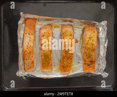 Bistecche di salmone fatte in casa, arrostite al forno, filetto con olio d'oliva su foglio di alluminio, vista ravvicinata della ricetta Flat Lay Foto Stock