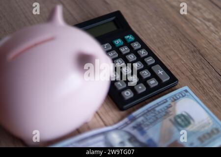 Immagine ravvicinata del salvadanaio, della calcolatrice e del denaro su un tavolo di legno. Concetto finanziario. Foto Stock