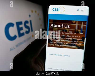 Persona in possesso di cellulare con pagina web della Confederazione europea dei sindacati indipendenti (CESI) con logo. Concentrarsi sul centro del display del telefono. Foto Stock