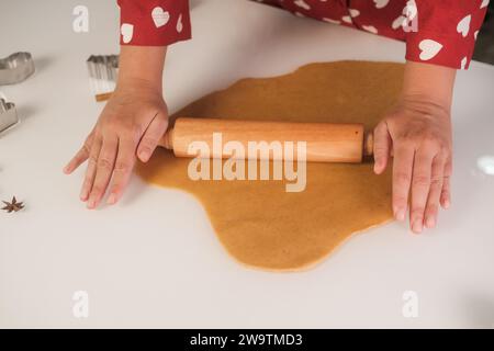 Primo piano delle mani di una giovane donna che stende l'impasto del pan di zenzero con un mattarello Foto Stock