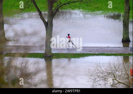 Runner corre lungo il fiume Severn, che ha fatto irruzione le sue rive e ha allagato parte del Quarry Park a Shrewsbury, nello Shropshire. Foto Stock