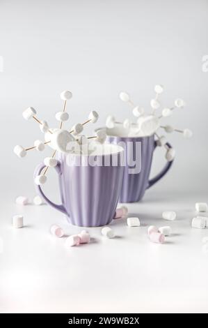 Tazze viola con caffè caldo e marshmallow. Due tazze con marshmallow a fiocco di neve. Foto Stock