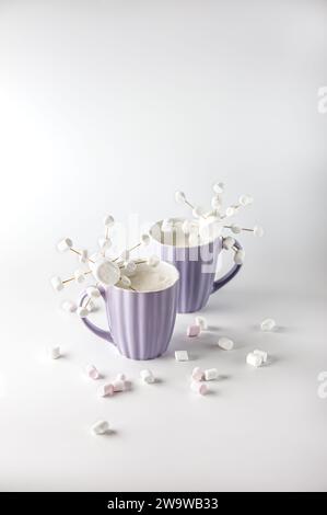 Tazze viola con caffè caldo e marshmallow. Due tazze con marshmallow a fiocco di neve. Foto Stock