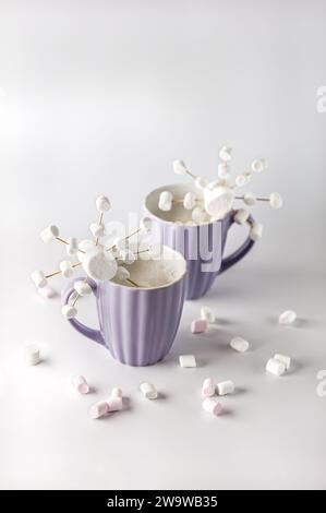 Tazze viola con caffè caldo e marshmallow. Due tazze con marshmallow a fiocco di neve. Foto Stock