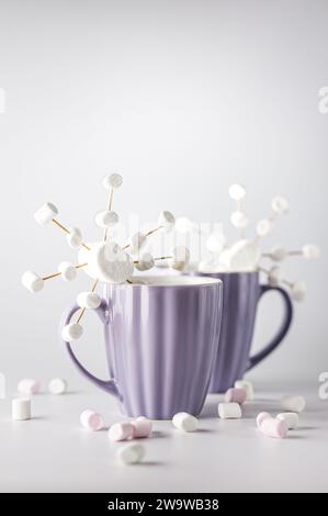 Tazze viola con caffè caldo e marshmallow. Due tazze con marshmallow a fiocco di neve. Foto Stock