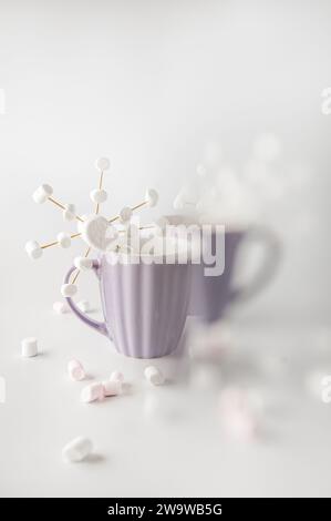 Tazze viola con caffè caldo e marshmallow. Due tazze con marshmallow a fiocco di neve. Sfoca parte dell'immagine. Foto Stock