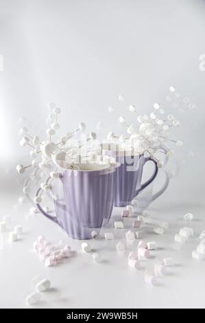 Tazze viola con caffè caldo e marshmallow. Due tazze con marshmallow a fiocco di neve. Effetto caleidoscopio. Foto Stock