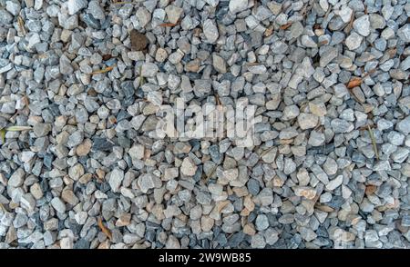 Strada all'aperto in ghiaia. Primo piano della consistenza della ghiaia. Schema pietra. Terreno di piccole rocce. Roccia frantumata. Fondo e texture grigio ghiaia. Foto Stock