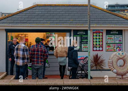 Una bancarella di cibo e bevande sul lungomare di Teignmouth in prima serata con i clienti in attesa di essere serviti. Foto Stock