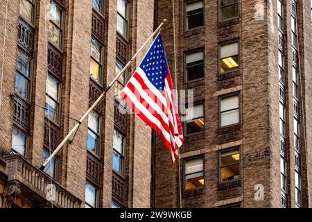 La bella grande bandiera americana che sventola sugli edifici dei grattacieli del quartiere di Manhattan nella grande Mela, simbolo di New York. Foto Stock