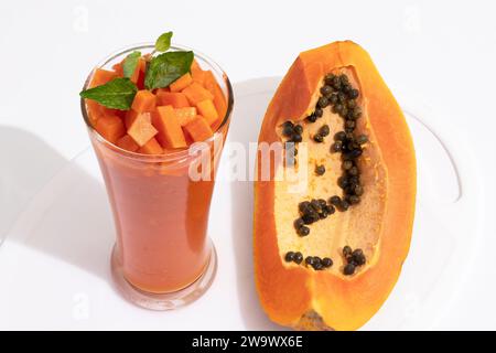 Papaya - frullati con succo di mango in tazze di vetro su tavolo bianco: Delizie della frutta tropicale con scintillante sfondo bokeh, perfette per vivaci e rinfrescanti Foto Stock