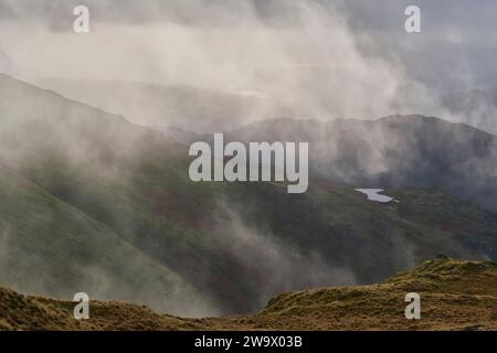 Nuvole basse che abbracciano Heron Pike e Alcock Tarn viste dalle pendici inferiori di Great Rigg, Grasmere, Lake District, Cumbria Foto Stock