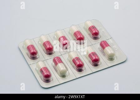 Capsule mediche rosso bianco in blister primo piano contro bianco Foto Stock