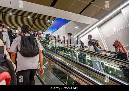 I turisti siedono civilizzati sulle scale mobili della metropolitana di Kuala Lumpur in Malesia Foto Stock