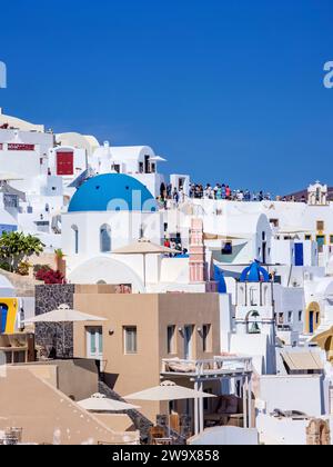 Ammira le chiese a cupola blu della Resurrezione del Signore e di San Spyridon, il villaggio di Oia, Santorini o l'isola di Thira, le Cicladi, la Grecia Foto Stock