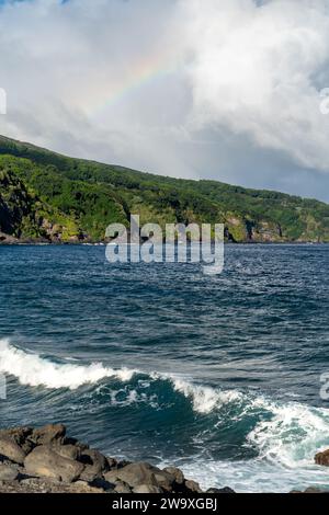 Un brillante arcobaleno si estende attraverso il cielo sopra le scogliere costiere del Parco Nazionale di Haleakalā, visto dall'autostrada Piilani a Maui. Foto Stock