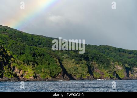 Un brillante arcobaleno si estende attraverso il cielo sopra le scogliere costiere del Parco Nazionale di Haleakalā, visto dall'autostrada Piilani a Maui. Foto Stock