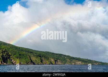 Un brillante arcobaleno si estende attraverso il cielo sopra le scogliere costiere del Parco Nazionale di Haleakalā, visto dall'autostrada Piilani a Maui. Foto Stock