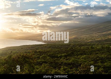 Gli ultimi raggi di un tramonto di Maui bagnano il paesaggio nella luce dorata lungo l'autostrada Piilani, accentuando la splendida topografia e il tranquillo oceano Foto Stock