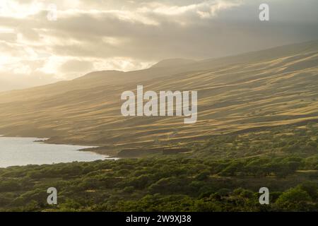 Gli ultimi raggi di un tramonto di Maui bagnano il paesaggio nella luce dorata lungo l'autostrada Piilani, accentuando la splendida topografia e il tranquillo oceano Foto Stock