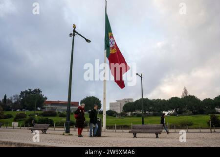 Lisbona, Portogallo. 30 dicembre 2023. La gente cammina vicino a una bandiera del Portogallo situata nelle vicinanze del parco Edoardo VII a Lisbona. Credito: SOPA Images Limited/Alamy Live News Foto Stock