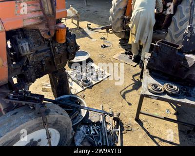 Meccanico del trattore in fase di revisione del motore del trattore in officina: 04 dicembre 2023 - Swat, Pakistan. Foto Stock