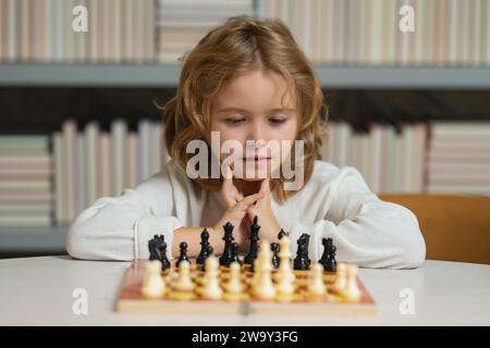 Il bambino chessman gioca a scacchi, scacco matto. Sviluppo precoce dei bambini. Ragazzo che gioca a scacchi a casa. Ritratto da vicino, faccia divertente Foto Stock