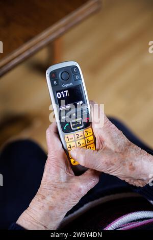 Norden, Germania. 28 dicembre 2023. Una signora anziana gestisce un telefono riservato agli anziani con pulsanti di selezione rapida. Crediti: Matthias Balk/dpa/Alamy Live News Foto Stock