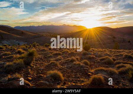 Vista panoramica del tramonto con esplosione di sole dalle catene montuose all'Hucks Lookout all'interno del Parco Nazionale Ikara-Flinders Ranges, Australia meridionale. Looki Foto Stock