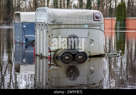 Lilienthal, Germania. 31 dicembre 2023. Due rimorchi per cavalli si trovano in un parcheggio allagato vicino al fiume Wörpe a Lilienthal. Mentre l'inondazione del fiume minacciava di infrangere una diga, centinaia di residenti nelle aree residenziali dietro hanno dovuto lasciare le loro case. Crediti: Focke Strangmann/dpa/Alamy Live News Foto Stock