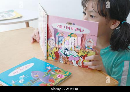 Asian Girl che legge un libro in lingua coreana Hangul. Foto Stock