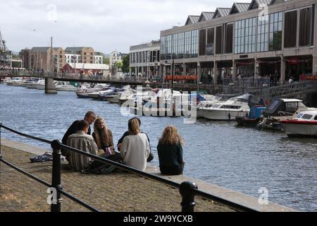 Bristol, Somerset, Regno Unito 06 16 2018 giovani siedono insieme all'Harbourside di Bristol, Regno Unito Foto Stock