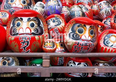 Una vista ravvicinata di una pila di bambole daruma tradizionali giapponesi al Tempio Shorinzan Daruma-ji nella prefettura di Gunma, Giappone. Foto Stock