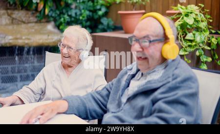 Coppia anziana che ascolta musica nel giardino della geriatrica Foto Stock