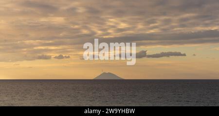 Una vista del Mar Tirreno al largo della Calabria con la silhouette dell'isola vulcanica di Stromboli al tramonto Foto Stock