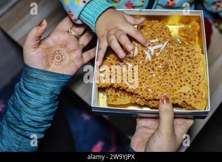 persone che condividono dettagli in primo piano con deliziosi dolci tradizionali indiani ghewar Foto Stock