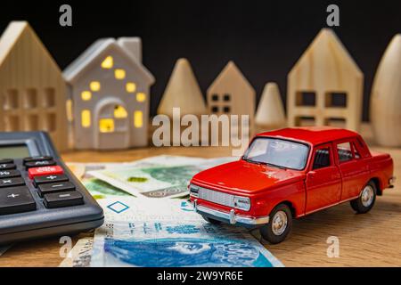 auto giocattolo con soldi polacchi, calcolatrice e casa di legno che aumentano le spese di vita inflazione crisi concetto auto tasso di interesse prestito Foto Stock