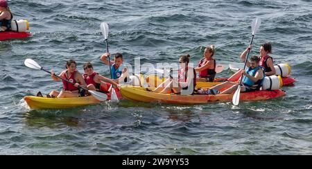 Persone che imparano a fare kayak causando una collisione con altri kayak. Fornells, Minorca Spagna Foto Stock