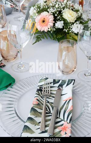 Disposizione dei tavoli preparata per un evento formale, un matrimonio o un'occasione speciale, decorata con dettagli a tema tropicale come fiori e tovaglie Foto Stock