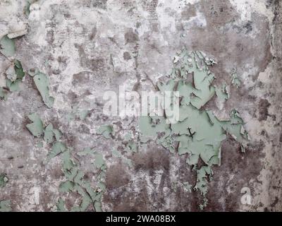 La vernice verde sfalda una parete di cemento colorata grigia. Foto Stock