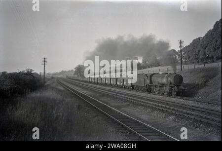 1950s, storica, una locomotiva a vapore che trainava carrozze merci a ovest di St Neots, Cambridge, Inghilterra, Regno Unito. Foto Stock