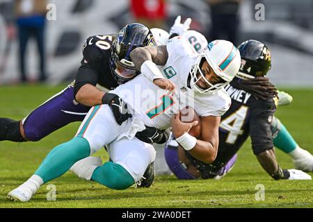 Baltimora, Stati Uniti. 31 dicembre 2023. Il quarterback dei Miami Dolphins tua Tagovailoa (1) fu licenziato dal linebacker dei Baltimore Ravens Kyle Van Noy (50) per una perdita di cinque yard durante il primo tempo al M&T Bank Stadium di Baltimora, Maryland, domenica 31 dicembre 2023. Foto di David Tulis/UPI credito: UPI/Alamy Live News Foto Stock