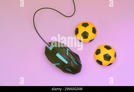 Due palloni da calcio con il mouse del computer su sfondo viola. Concetto di videogiochi, eSports, sport scommesse e gioco d'azzardo online Foto Stock