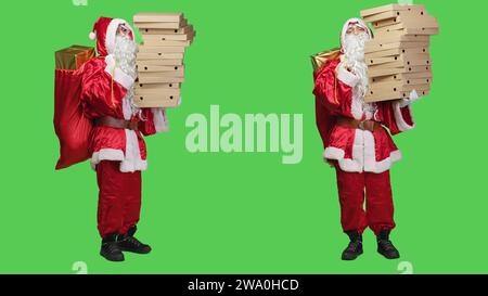 Saint nick con sacco e pizze di scatole per pizza, che lavora come fattorino vestito con il costume natalizio rosso di babbo natale. Persona con fast food e sacco di giocattoli in posa su schermo verde a tutto il corpo. Foto Stock