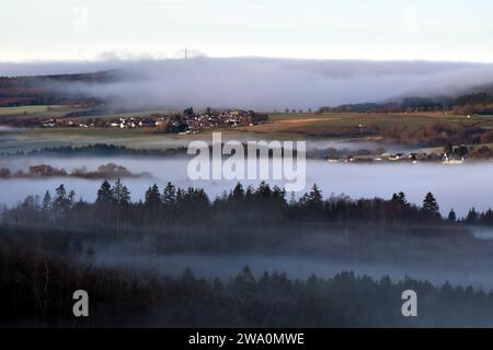 Paesaggio di Hunsrück con villaggi, foreste e prati ai margini del Parco Nazionale di Hunsrück-Hochwald con nebbia in una mattina d'inverno, Renania Foto Stock