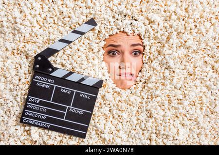 Foto dall'alto di una persona pazza terrorizzata che morde le labbra guarda la faccia del gesso di un film spaventoso isolato su sfondo pop corn Foto Stock